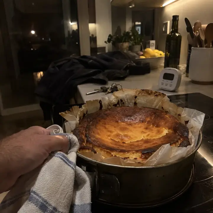 Tarta de queso al horno todavía en su molde con papel de horno tostado, en la cocina de noche