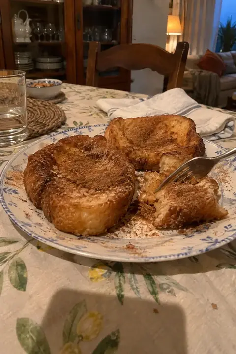 Plato de torrijas con canela en la mesa del comedor, con un tenedor ya en una de ellas